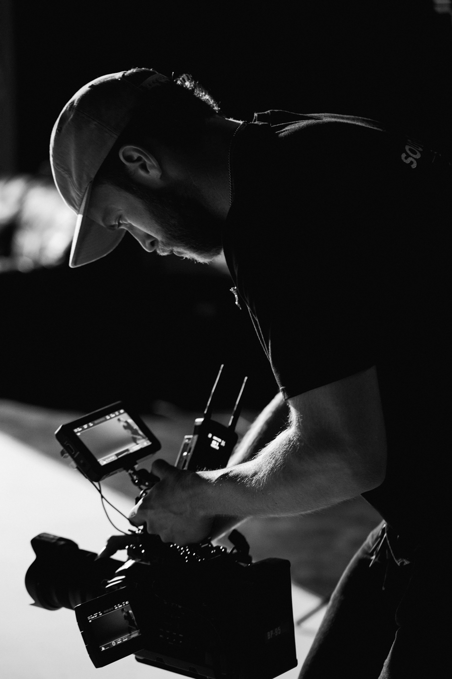 Camera operator with rig and monitors on a dark film set