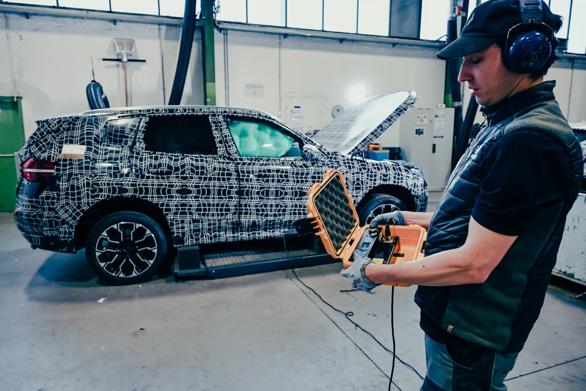 BMW technician working beside a camouflaged vehicle at the Recycling & Demontage Zentrum