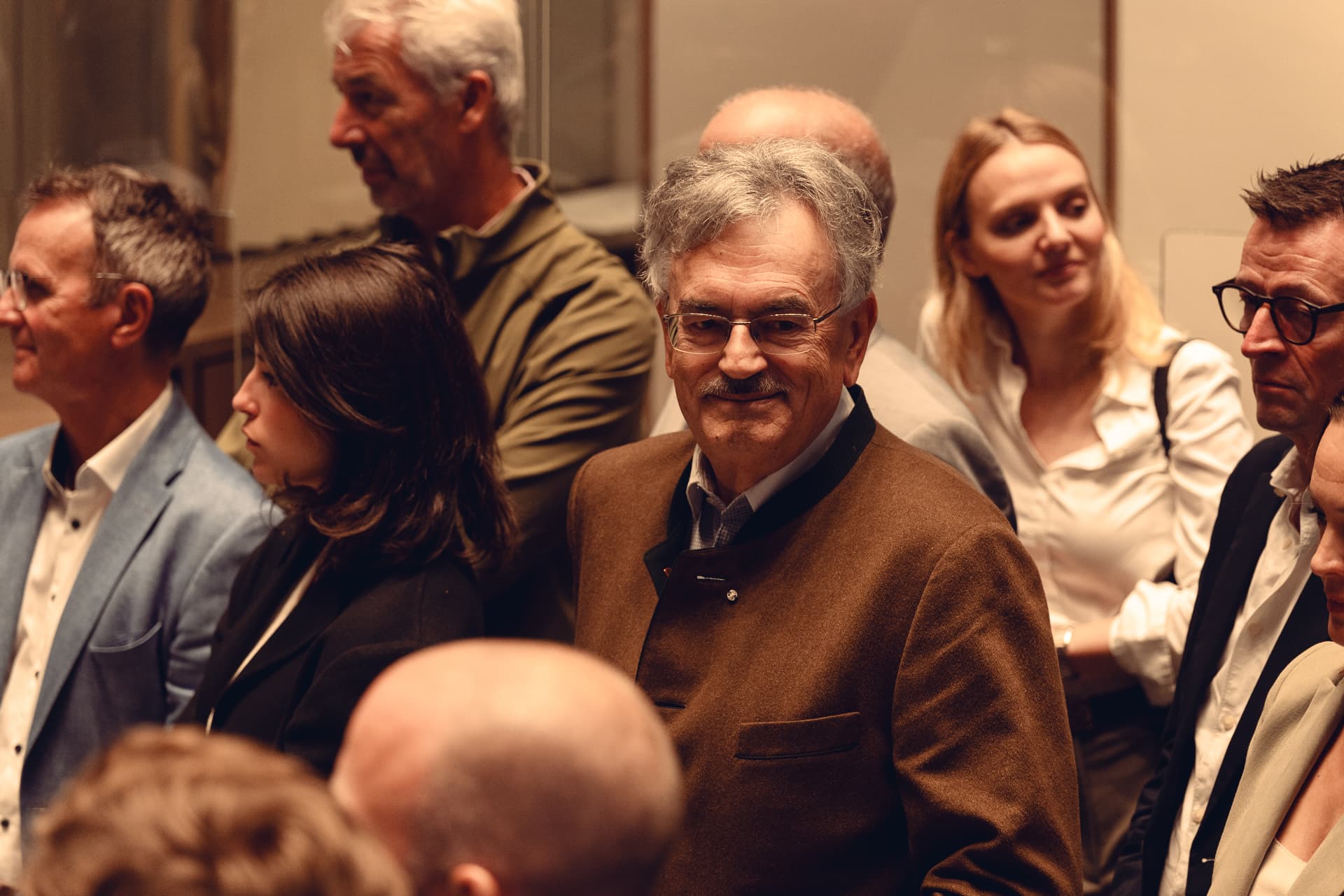 Guest in a traditional brown jacket smiling during the Herzog Max opening reception