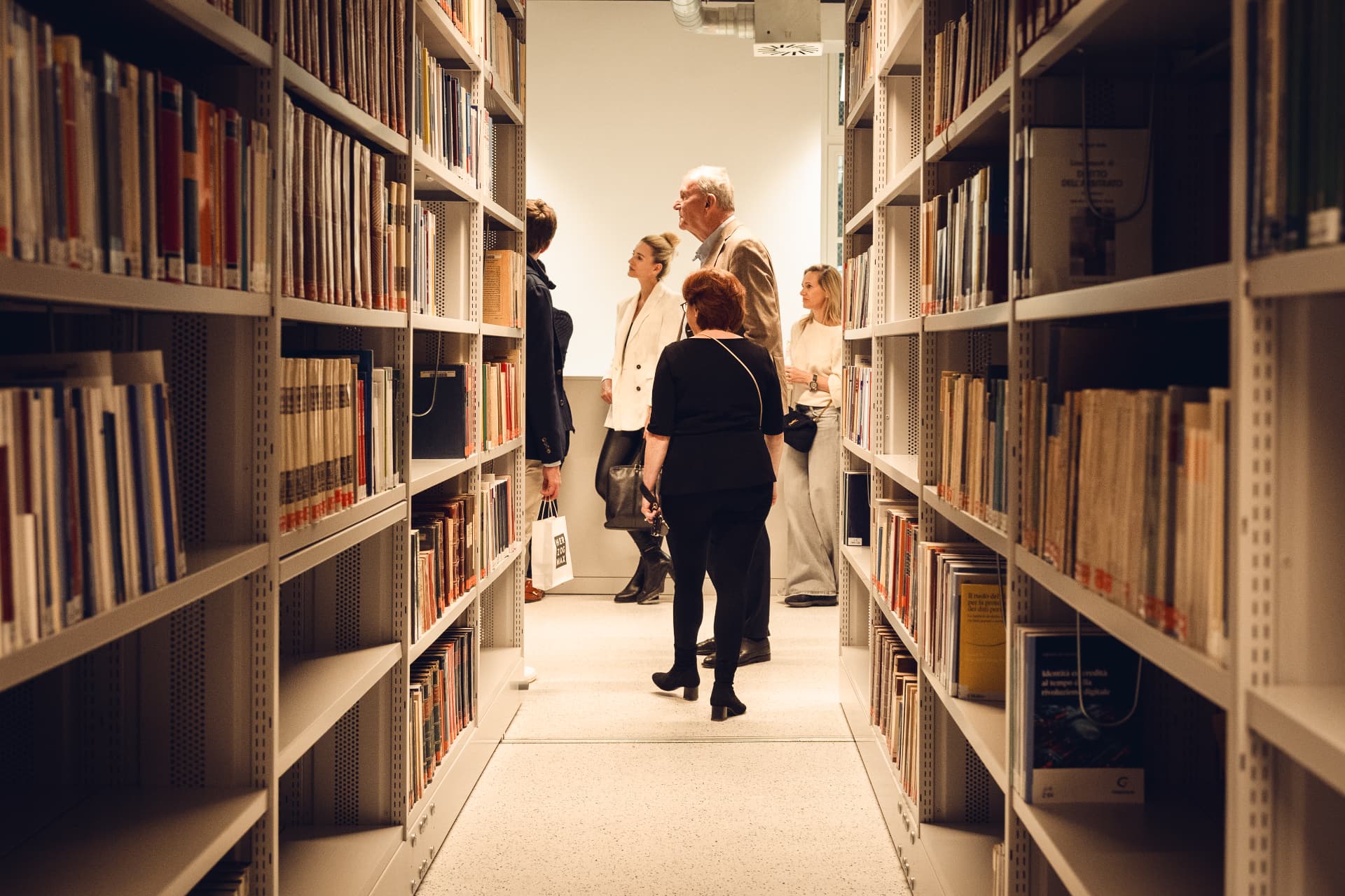 Guests on a tour through the Herzog Max library during the opening, photographed between the shelves