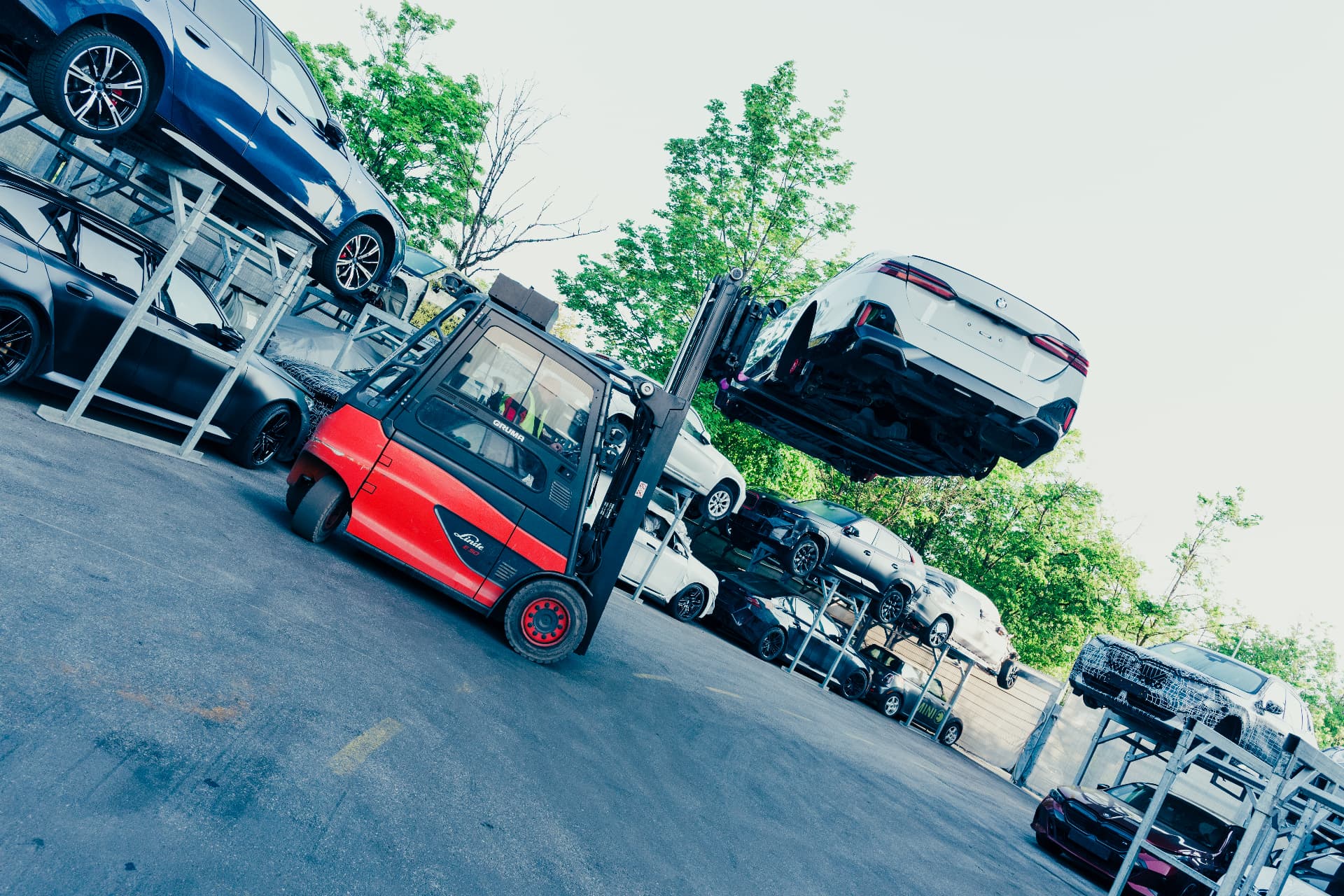 Forklift lifting a BMW vehicle among stacked vehicles at the Recycling & Demontage Zentrum