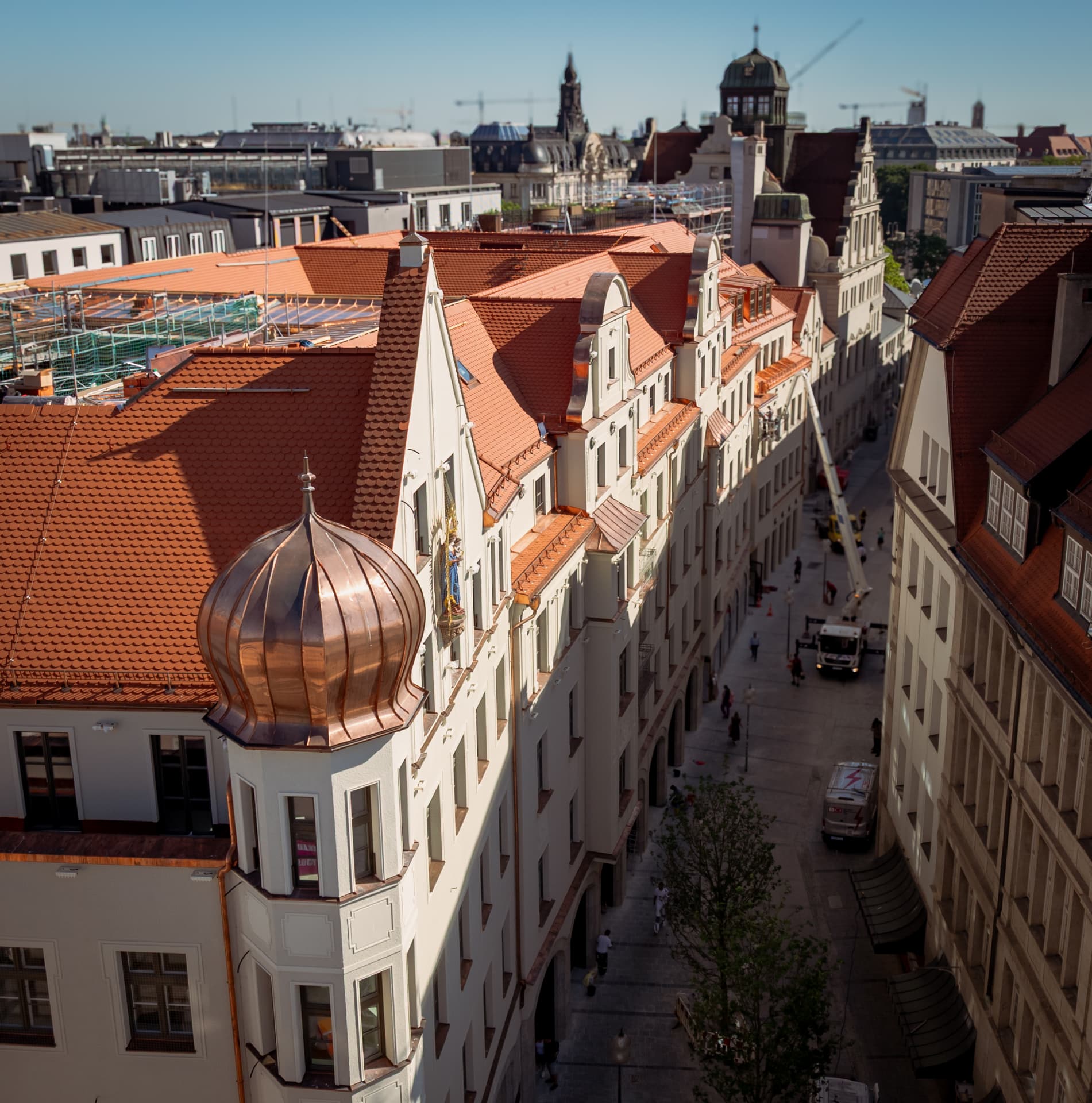 Herzog Max rooftop — copper dome and red tile roofs seen from above during construction