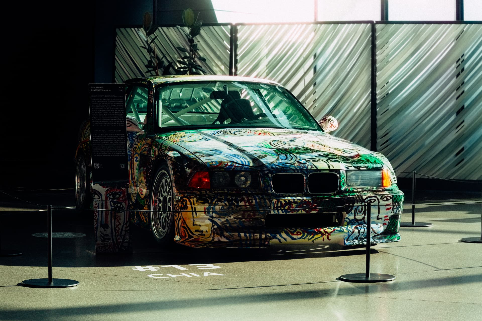 Painted BMW Art Car displayed in an architectural exhibition space at BMW Welt