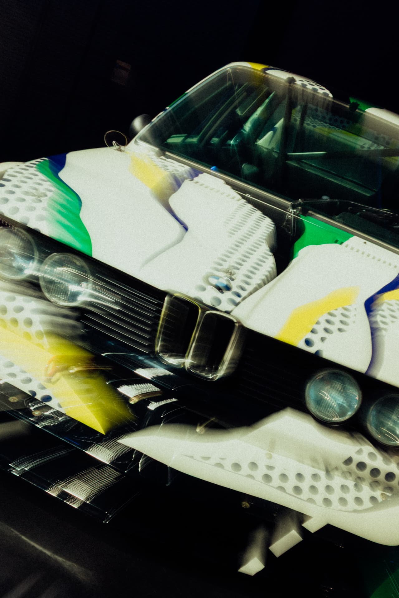 Portrait detail of a white BMW Art Car with green, yellow and blue painted bodywork