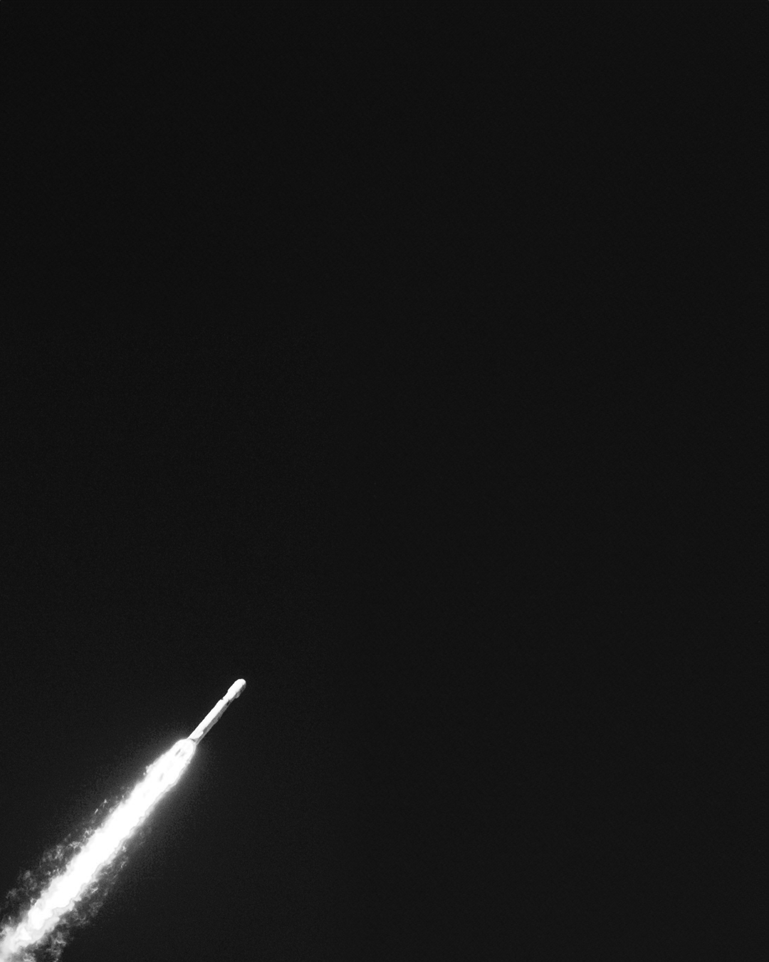 Black-and-white rocket launching into the night sky with a glowing exhaust trail