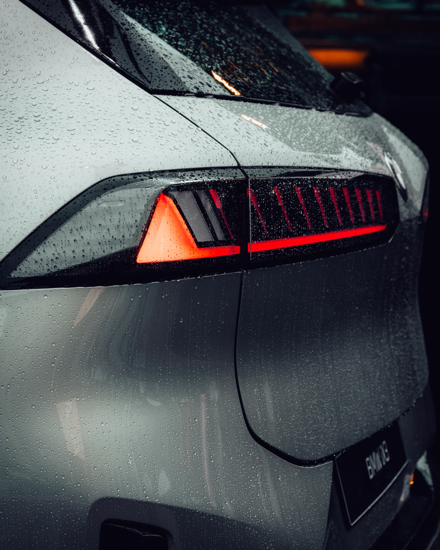 Rear light detail of the BMW iX3 in the rain with red light bars glowing