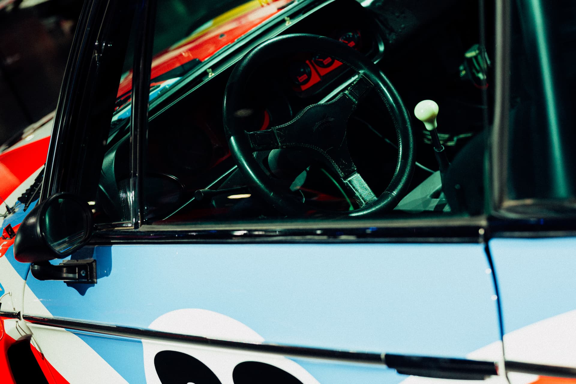 View through the window of a blue race-liveried BMW Art Car onto steering wheel and gear shift