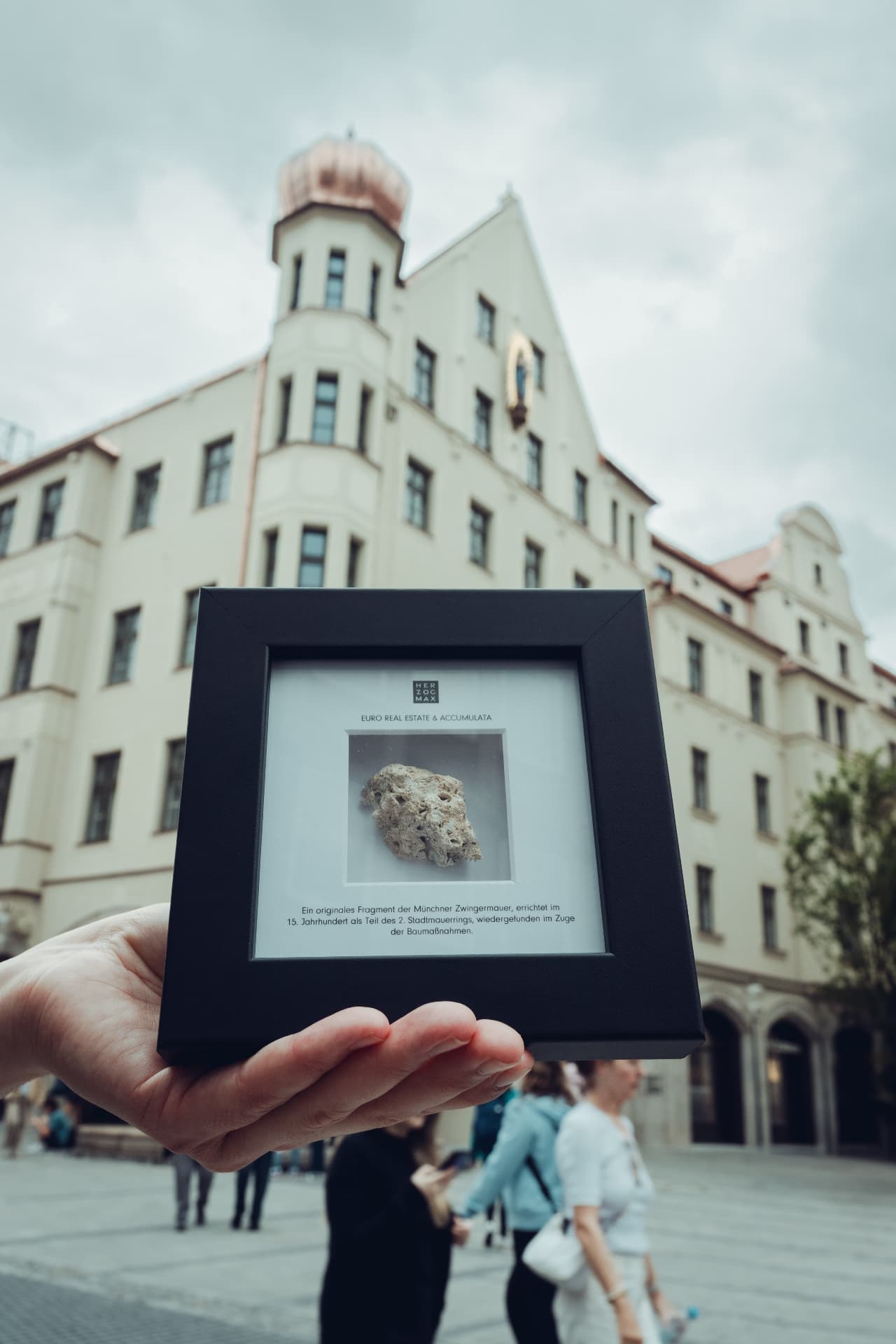 A framed fragment of the medieval Munich city wall held up in front of Herzog Max — a gift for the opening guests