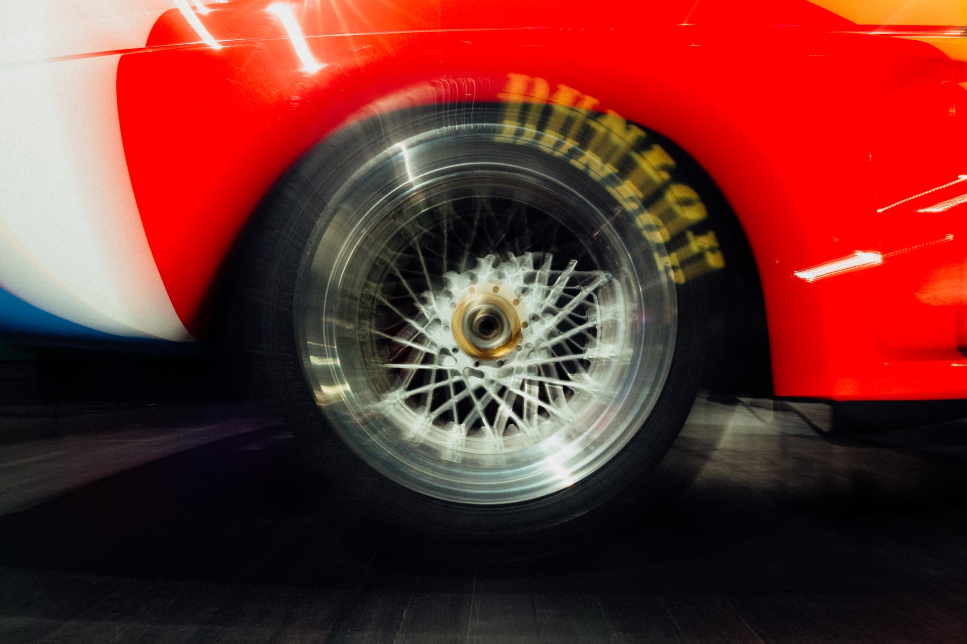Close view of a BMW Art Car wheel and red bodywork captured with motion blur